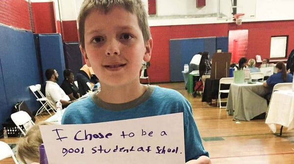 A US school kid holding a placard that reads "I chose to be a good student at school."